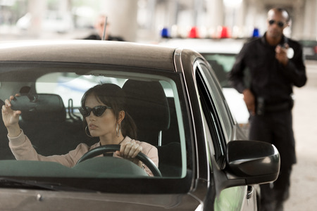 african american policeman approaching to car of young woman in sunglassesの写真素材