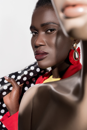 selective focus of beautiful african american woman with shopping bag looking at camera on whiteの写真素材