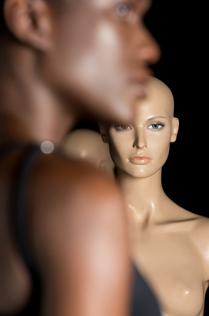 selective focus of young african american woman standing near dummies on blackの写真素材