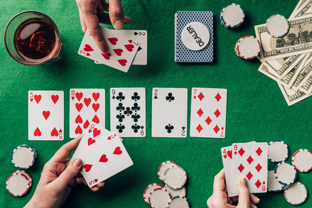 People playing poker by casino table with cards and chips