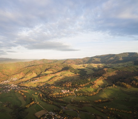 aerial view of beautiful green hills with trees and buildings at sunlight, Germanyの写真素材