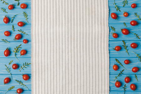top view of napkin and cherry tomatoes with arugula on blue tableの写真素材