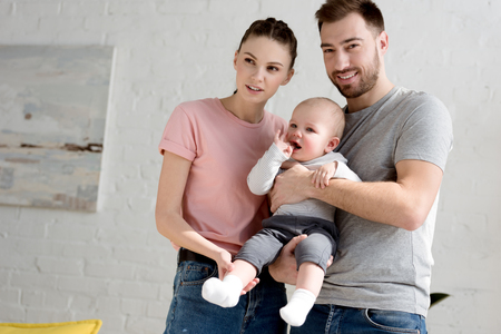young happy parents with little baby boy at homeの写真素材