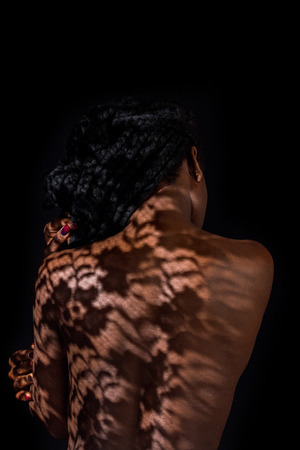 rear view of young african american woman with floral shadow on naked backの写真素材