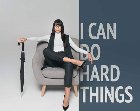 beautiful brunette businesswoman sitting on armchair with umbrella on gray with you can do hard thingsの写真素材