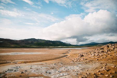 Beautiful Icelandic landscape with rocks on plain and scenic mountains at sunny dayの写真素材