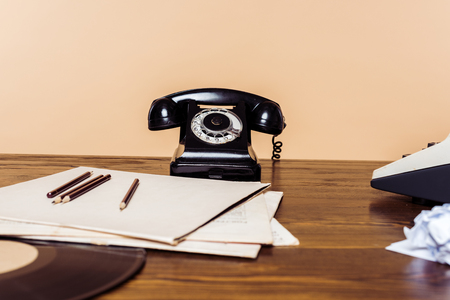 Closeup shot of rotary phone on wooden table with typewriter and vinyl disc on tableの写真素材