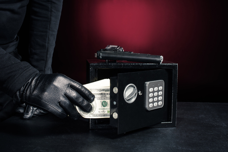 Close-up view of criminal opening safe with dollarsの写真素材