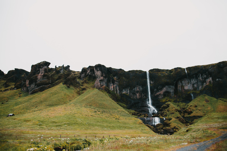 Beautiful scenic view of waterfall, rocks and green slopes in Icelandの写真素材