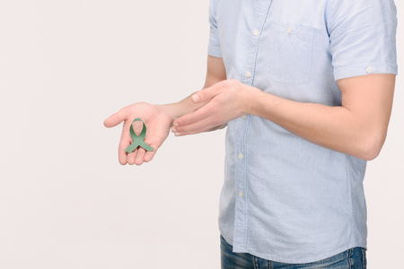 Cropped shot of man showing green ribbon isolated on white background, world health day conceptの写真素材