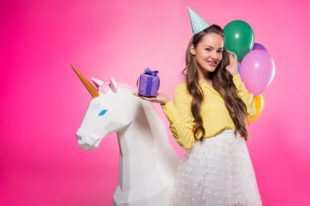 Beautiful woman with party hat and present isolated on pink backgroundの写真素材