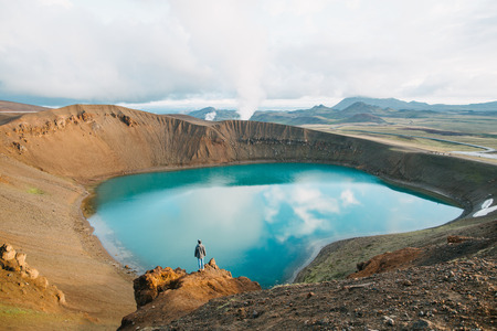 Back view of man looking at majestic volcanic lake in Iceland, Krafla, lake Viti