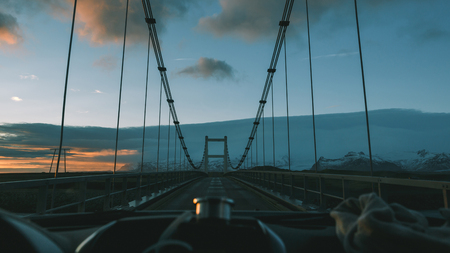 POV from car driving on bridge at sunset in Icelandの写真素材