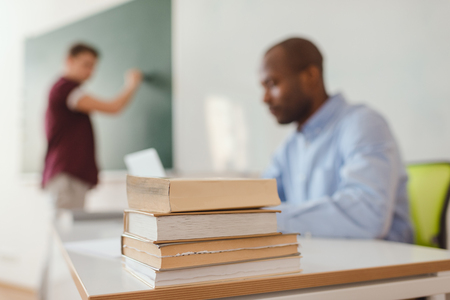 Close up shot of stack of books with teacher and high school student on behindの写真素材