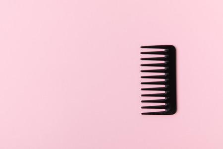 One black comb, isolated on light pink backgroundの写真素材