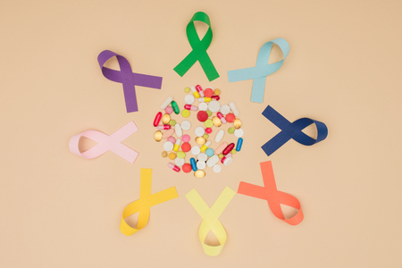 Flat lay with arranged pills and colorful ribbons around isolated on beige tabletop, world health day conceptの写真素材