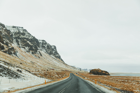 Beautiful Icelandic landscape with rocky hills and empty asphalt roadの写真素材