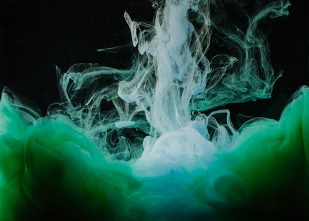 Close-up view of abstract white, green and blue ink on black backgroundの写真素材
