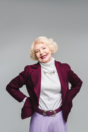 Beautiful senior woman in stylish jacket and turtleneck isolated on grey backgroundの写真素材
