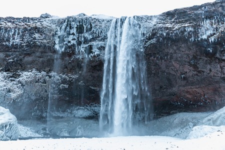 Spectacular view of Seljalandsfoss waterfall and rocks in snow and ice, Icelandの写真素材