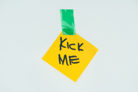 Close up view of note with kick me lettering and sticky tape isolated on grey background, April fools day conceptの写真素材