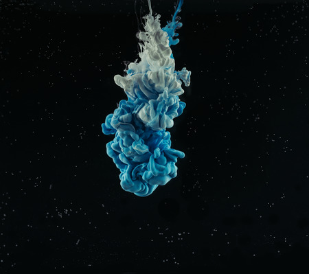 Close-up view of abstract blue and grey flowing ink on black backgroundの写真素材