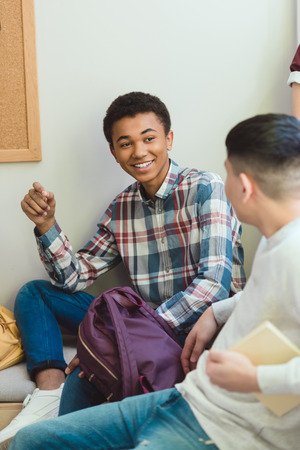 Smiling African American high school student talking to classmate during school breakの写真素材