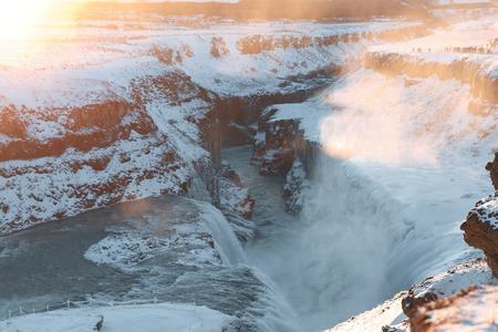 Majestic snow-covered Icelandic landscape with Gullfoss waterfall and rocks at sunriseの写真素材