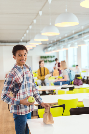 Smiling African American schoolboy at school cafeteriaの写真素材