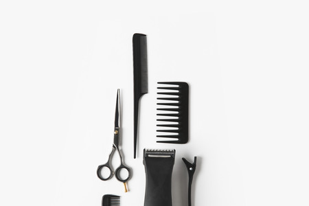 Flat lay with hair machine and hairdressing tools, on white background