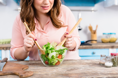 Partial view of overweight woman cooking fresh salad for dinner in kitchen at homeの写真素材