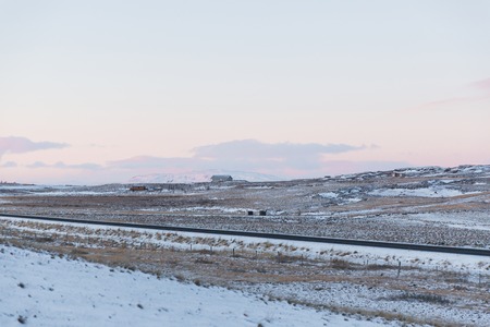 Beautiful snow-covered Icelandic landscape with houses and roadの写真素材
