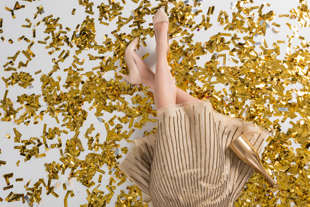 Cropped image of woman lying on golden confettiの写真素材