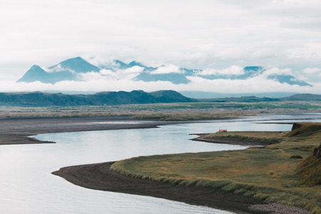 Beautiful landscape with wide river and mountain peaks in clouds, Icelandの写真素材
