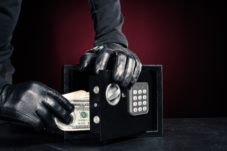 Close-up view of robber with stealing dollar banknotes from safe