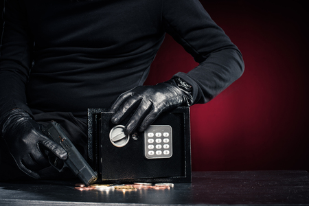 Close-up view of robber with gun taking bitcoin from safe boxの写真素材