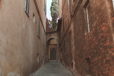 Archway between two buildings in historical quarter of Siennaの写真素材
