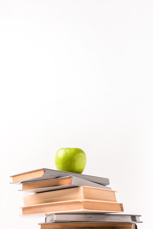 Low angle view of pile of books with apple on top isolated on white backgroundの写真素材