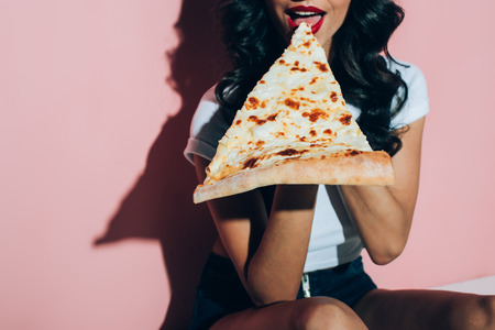 Partial view of woman eating pizza on pink backgroundの写真素材