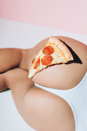 Partial view of piece of pizza on female bootyの写真素材
