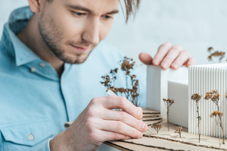 Selective focus of focused architect looking at self made building model in officeの写真素材