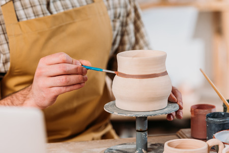 Cropped view on potter painting ceramic jug