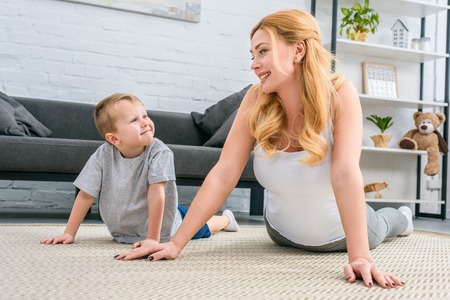 Happy mother and son practicing yoga in modern living roomの写真素材
