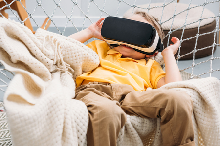 Little boy in rope hammock using virtual reality headset