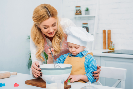 Happy mother holding son while he using hand beaterの写真素材