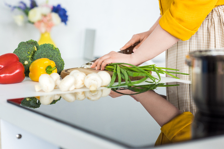 Cropped image of woman cutting green onion in kitchenの写真素材