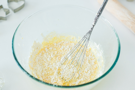 High angle view of bowl with whisk and dough in kitchen