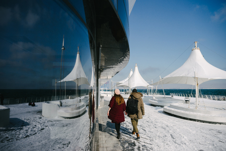 Stylish couple walking near glass building with reflectionの写真素材