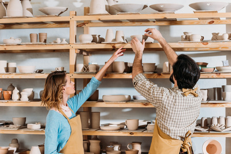 Two potters with ceramic dishware in workshopの写真素材