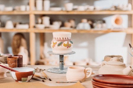 Traditional painted ceramic jug on table in pottery workshop